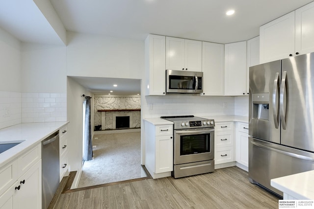 kitchen with light hardwood / wood-style flooring, stainless steel appliances, and white cabinets