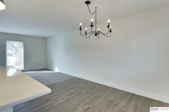 unfurnished dining area featuring dark hardwood / wood-style flooring and a chandelier