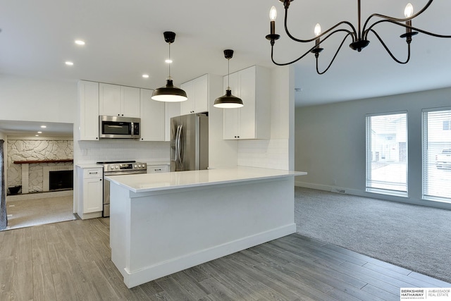 kitchen with appliances with stainless steel finishes, tasteful backsplash, white cabinets, decorative light fixtures, and a chandelier