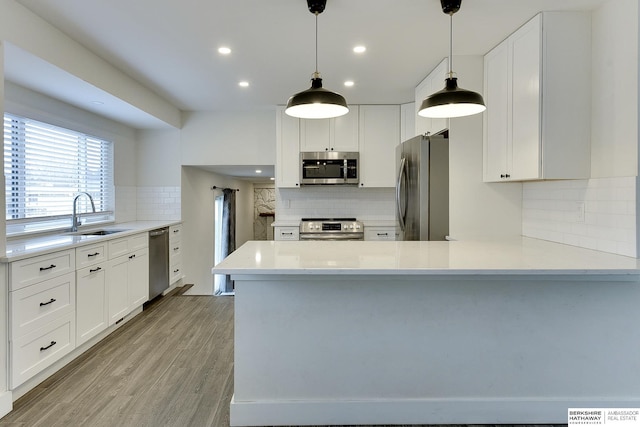 kitchen with white cabinetry, sink, stainless steel appliances, and kitchen peninsula