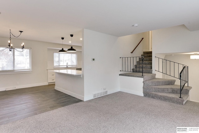 unfurnished living room with dark hardwood / wood-style flooring, sink, and a notable chandelier