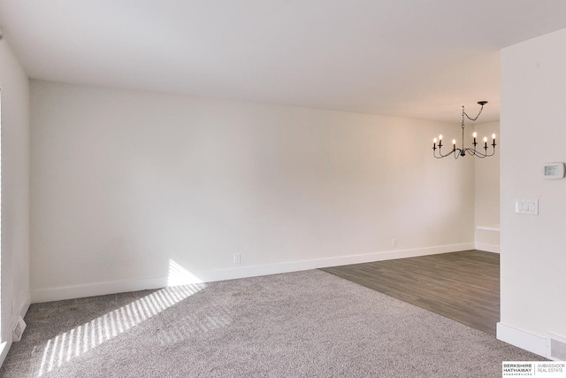 unfurnished room featuring an inviting chandelier and dark colored carpet