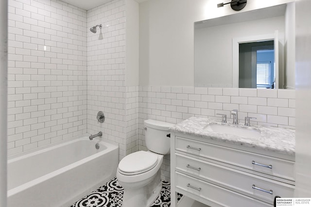 full bathroom featuring tiled shower / bath, vanity, toilet, and tile walls