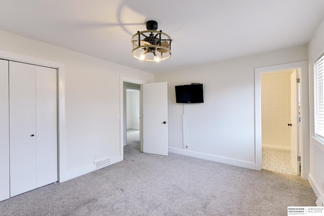 unfurnished bedroom with light colored carpet, ensuite bathroom, and a closet