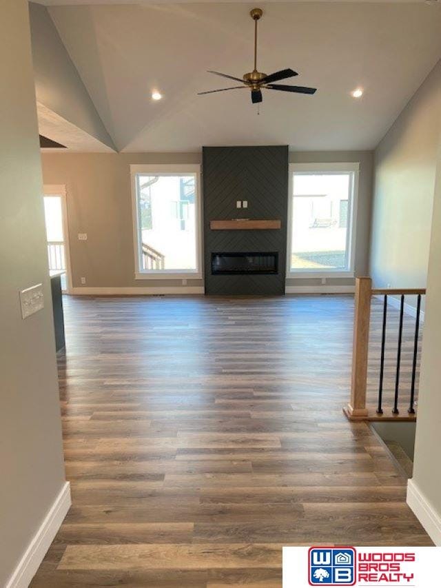 unfurnished living room with ceiling fan, lofted ceiling, a fireplace, and dark hardwood / wood-style flooring