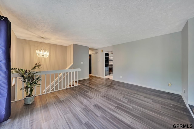 spare room with hardwood / wood-style floors, a notable chandelier, and a textured ceiling