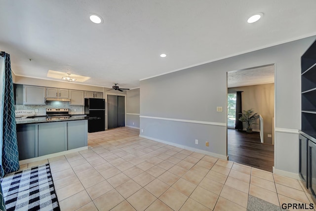 kitchen with gray cabinetry, black fridge, light tile patterned floors, stainless steel electric stove, and decorative backsplash