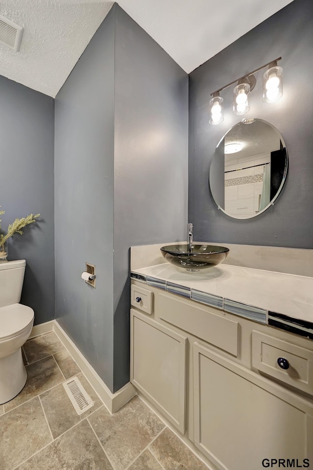 bathroom featuring vanity, a textured ceiling, and toilet