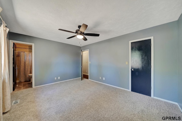 unfurnished bedroom with connected bathroom, carpet flooring, and a textured ceiling