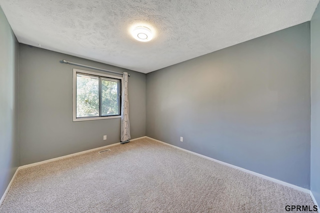 unfurnished room with carpet and a textured ceiling