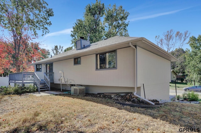 rear view of house featuring central AC unit, a yard, and a deck