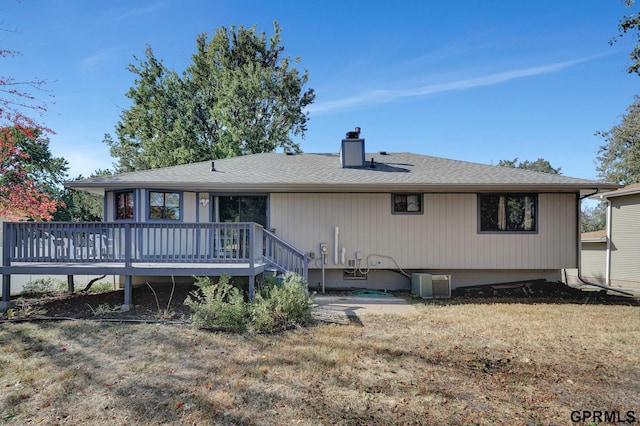 rear view of house featuring a wooden deck, central AC, and a lawn