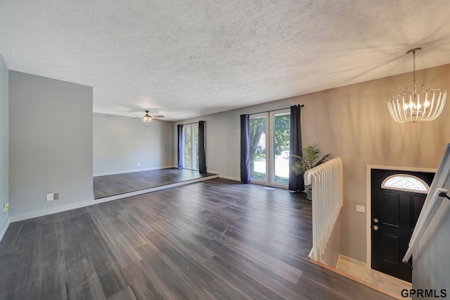 foyer with ceiling fan with notable chandelier, dark wood-type flooring, and a textured ceiling