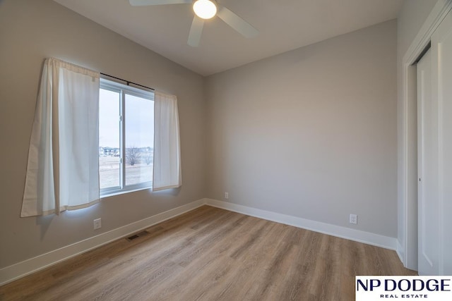 empty room with ceiling fan and light hardwood / wood-style flooring