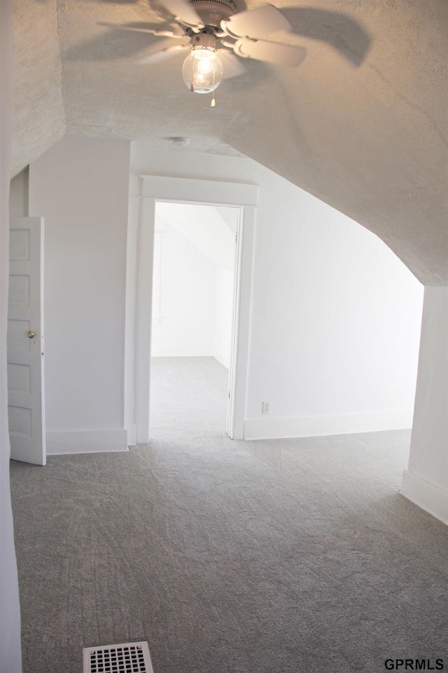 additional living space with vaulted ceiling, carpet floors, ceiling fan, and a textured ceiling