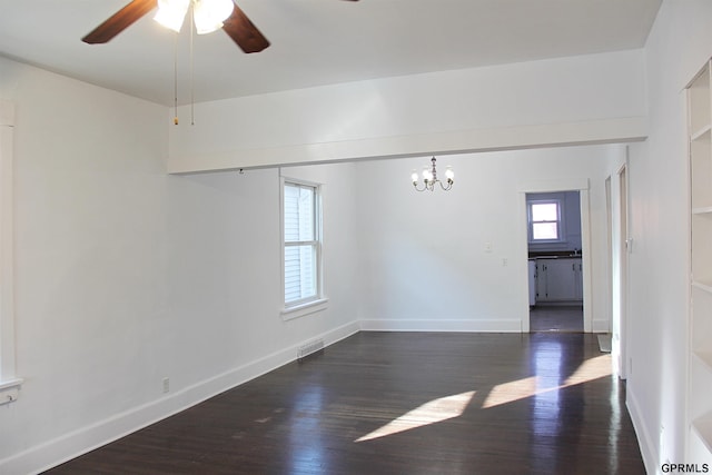 empty room with dark hardwood / wood-style flooring and ceiling fan with notable chandelier