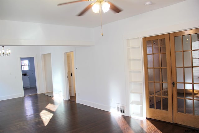 unfurnished room featuring dark wood-type flooring, ceiling fan with notable chandelier, and built in shelves