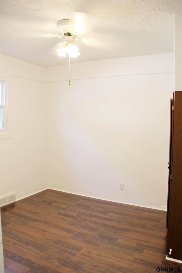 spare room featuring dark hardwood / wood-style floors and a textured ceiling