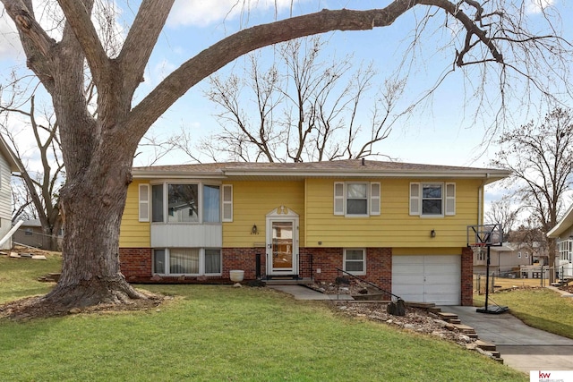 split foyer home featuring brick siding, an attached garage, concrete driveway, and a front yard