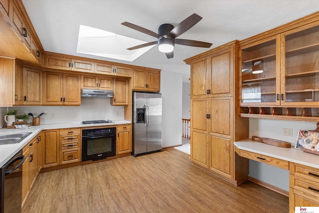 kitchen with black appliances, light countertops, light wood-style floors, built in desk, and under cabinet range hood