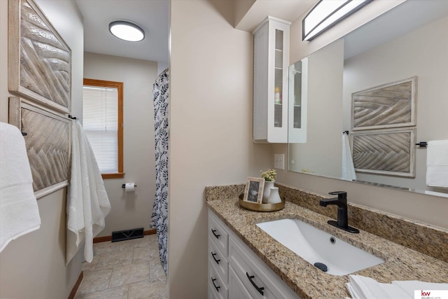 full bath featuring visible vents, vanity, stone finish flooring, and baseboards