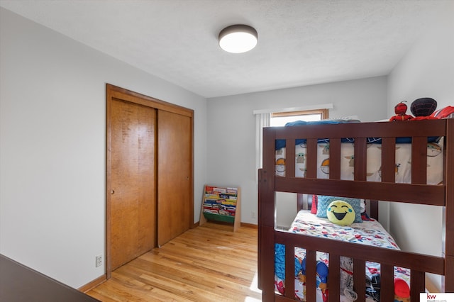 bedroom with light wood-style flooring, baseboards, and a closet