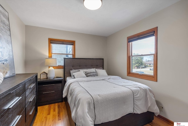 bedroom with light wood-style flooring, multiple windows, and baseboards