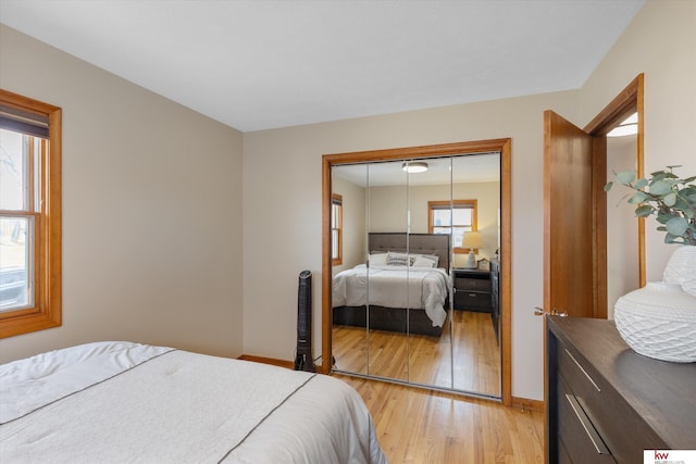 bedroom with a closet, baseboards, and light wood-style floors