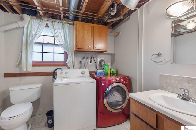 clothes washing area with washer and dryer, tile walls, laundry area, and a sink