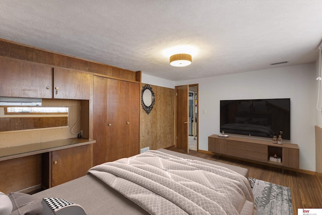 bedroom featuring a closet, a textured ceiling, visible vents, and wood finished floors