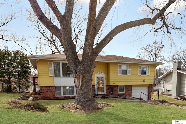 split foyer home with a front lawn, an attached garage, and brick siding