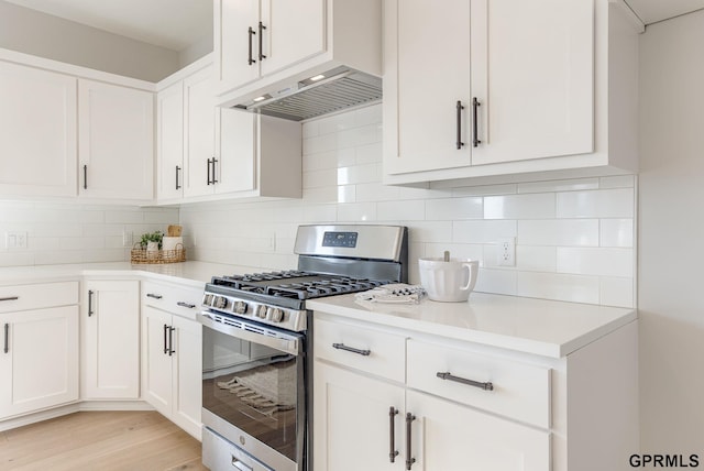 kitchen with stainless steel gas range, extractor fan, decorative backsplash, and white cabinets