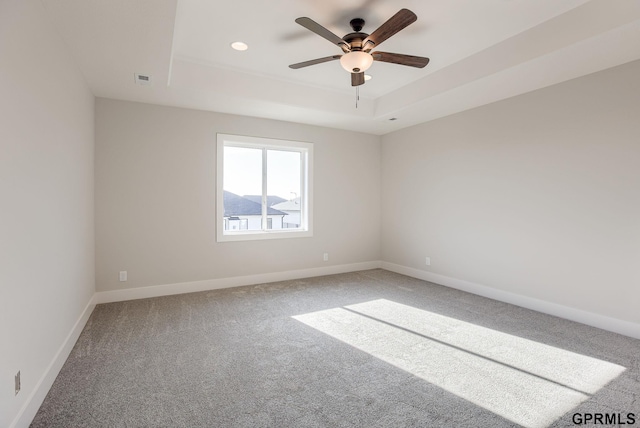 empty room featuring ceiling fan, carpet flooring, and a raised ceiling