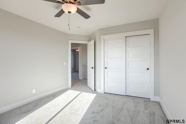 unfurnished bedroom featuring light carpet, a closet, and ceiling fan