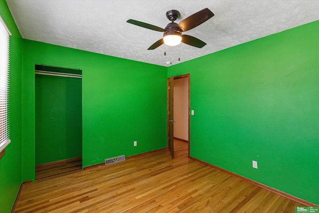 unfurnished bedroom with ceiling fan, a textured ceiling, and light wood-type flooring