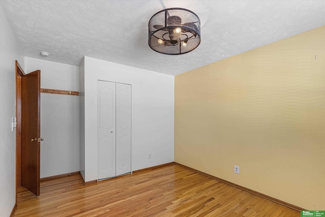 unfurnished bedroom featuring a textured ceiling, light hardwood / wood-style floors, and a closet