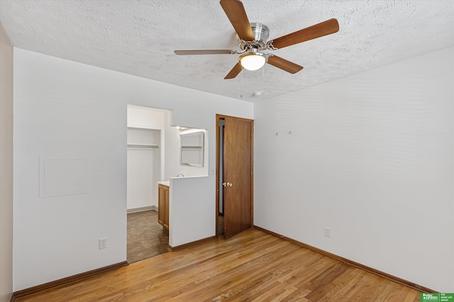 unfurnished bedroom with ceiling fan, a closet, a textured ceiling, and light wood-type flooring