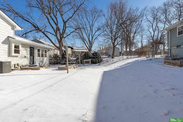 yard covered in snow with a storage unit and central AC unit