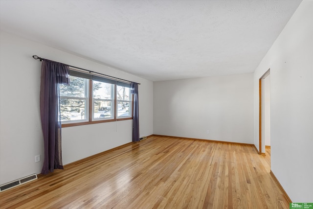 unfurnished room with a textured ceiling and light wood-type flooring