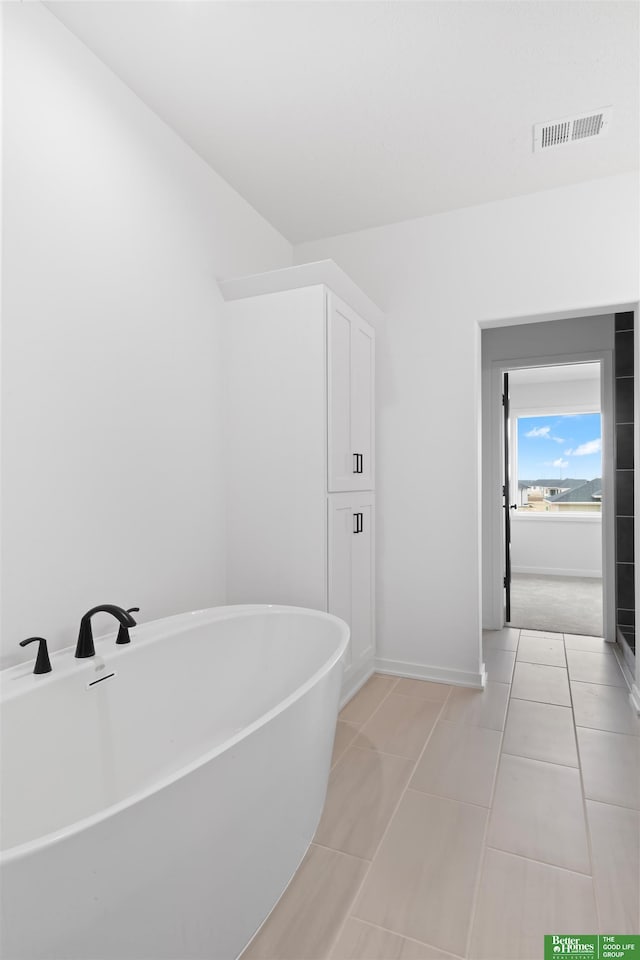 bathroom with a washtub and tile patterned floors