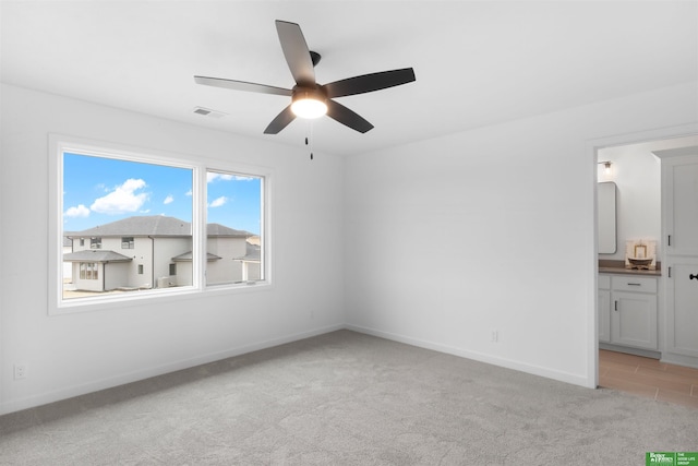 interior space featuring ceiling fan, ensuite bathroom, and light carpet