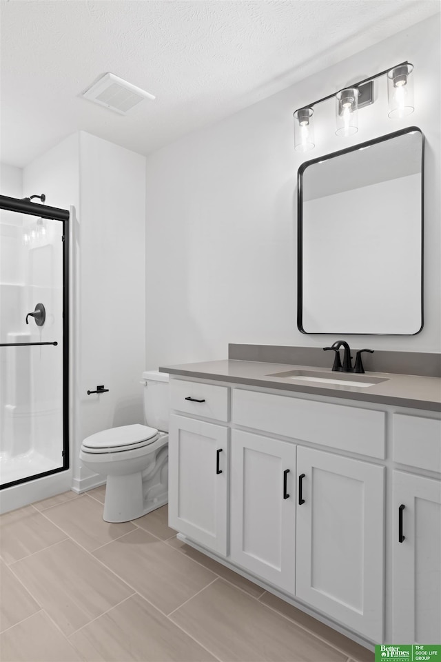 bathroom featuring vanity, a textured ceiling, a shower with door, and toilet