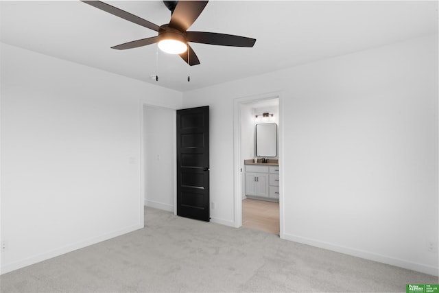 unfurnished bedroom featuring connected bathroom, sink, light carpet, and ceiling fan