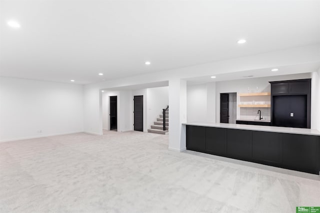 unfurnished living room featuring light colored carpet and wet bar