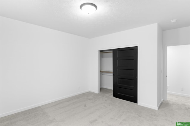 unfurnished bedroom featuring light colored carpet, a textured ceiling, and a closet