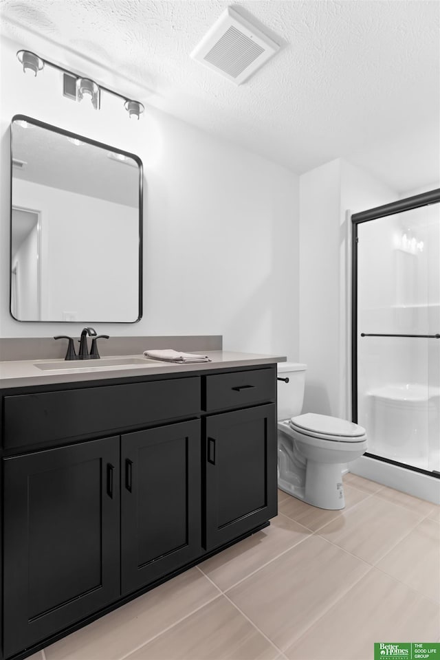 bathroom with vanity, toilet, a shower with door, and a textured ceiling