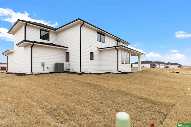 rear view of house featuring central AC and a lawn