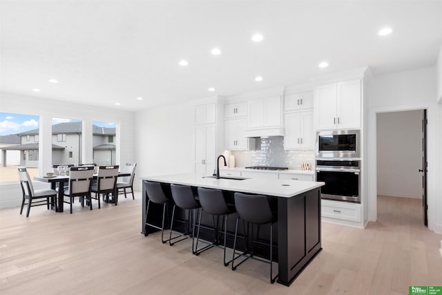 kitchen with white cabinetry, appliances with stainless steel finishes, a kitchen island with sink, and sink