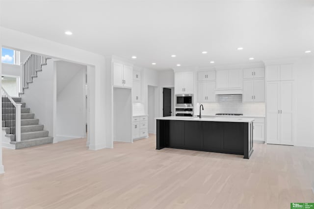 kitchen featuring a kitchen island with sink, sink, white cabinets, and appliances with stainless steel finishes