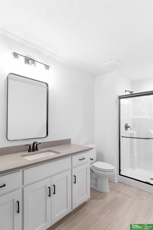 bathroom featuring vanity, an enclosed shower, and toilet